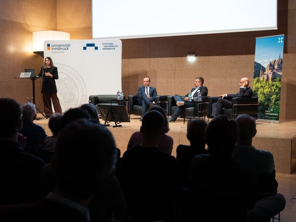 Foto von Vortragenden auf der Bühne und Publikum