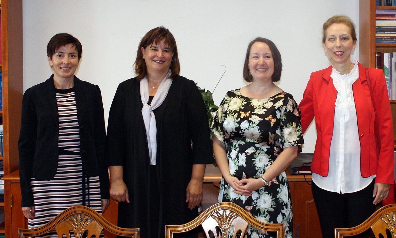 Vier Frauen stehen für ein Gruppenfoto zusammen vor einer weißen Wand.