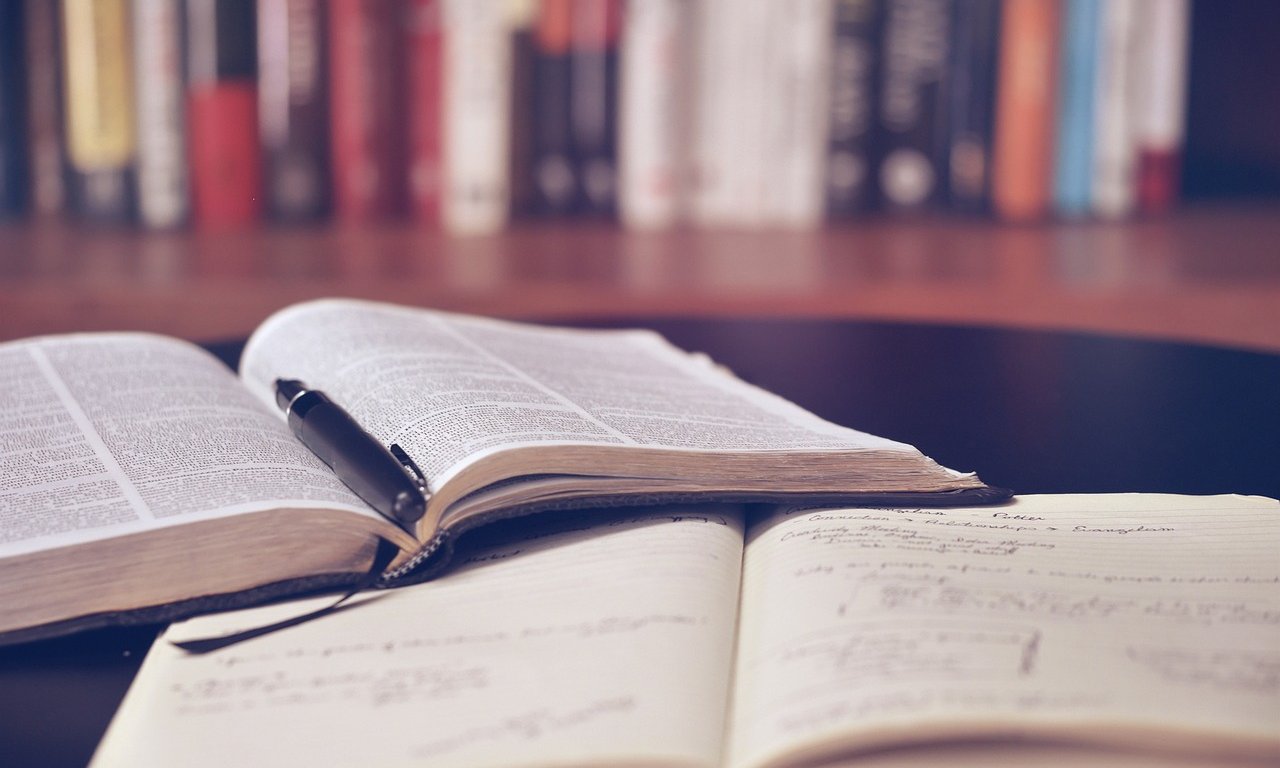 Aufgeschlagene Bücher liegen auf Schreibtisch