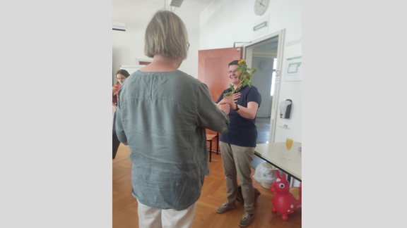 Zu sehen sind die Mitglieder des Instituts beim Sommerumtrunk. Es werden Blumen zum Geburtstag überreicht.