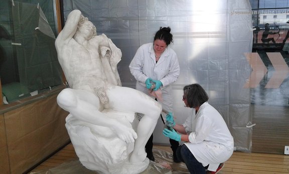 Wissenschaftlerinnen restaurieren eine Statue.