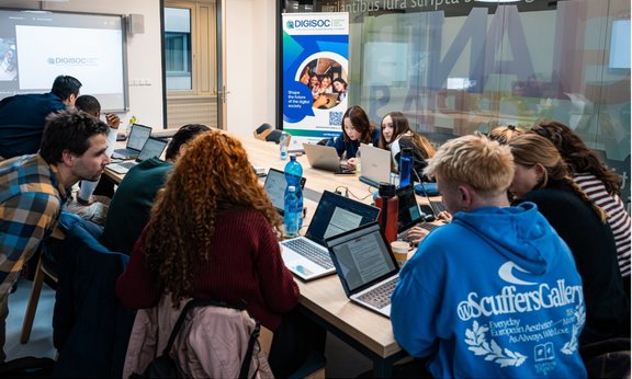 Mehrere Studierende sitzen an einem Tisch und diskutieren