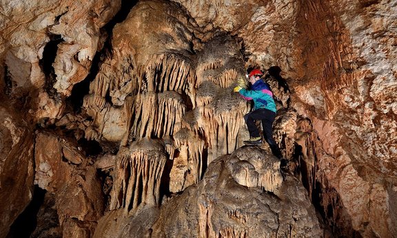 Eine Person in einer Höhle stehend und Tropfsteine untersuchend