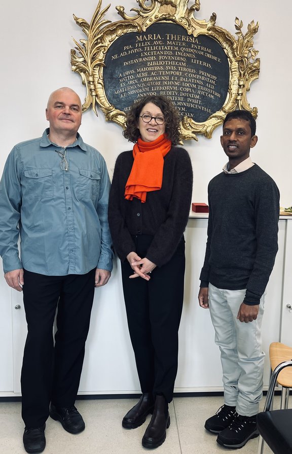 Gruppenfoto mit drei Personen im historischen Altbau der ULB.