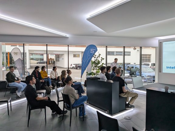 zeigt den Raum von hinten mit allen Teilnehmer:innen