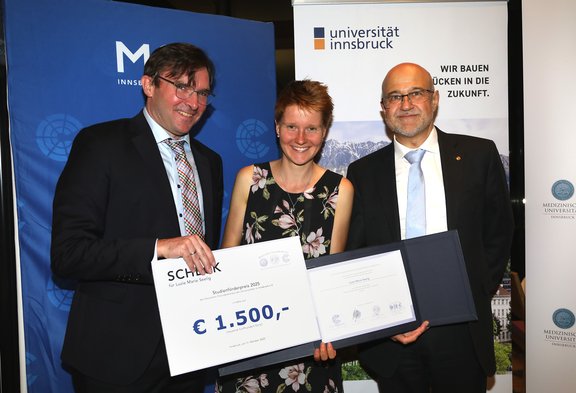 Drei Personen mit Urkunde und Scheck