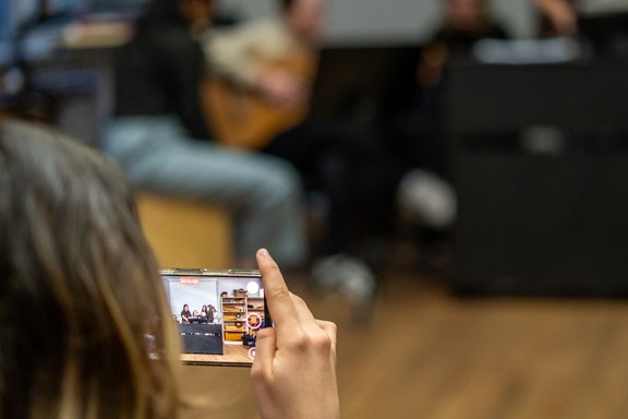Eine Hand hält ein Handy und filmt.