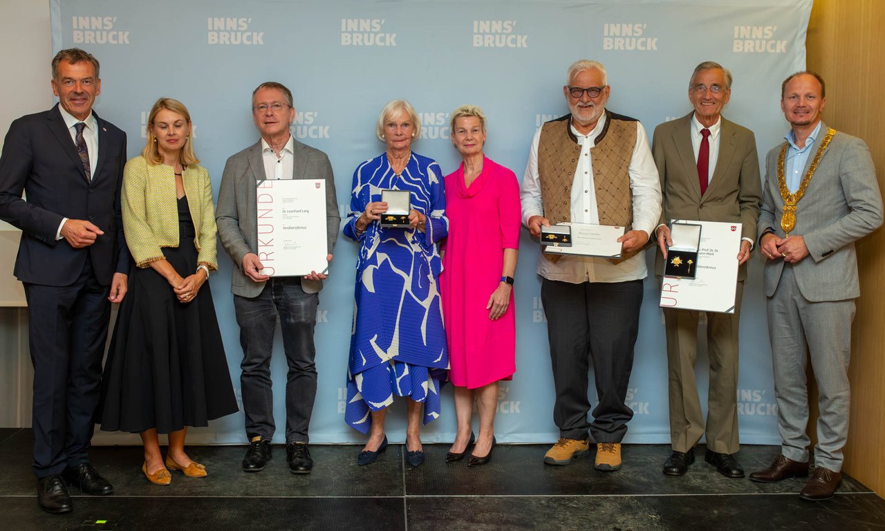 Mehrere Personen stehen in einer Reihe, einige halten Urkunden in der Hand.