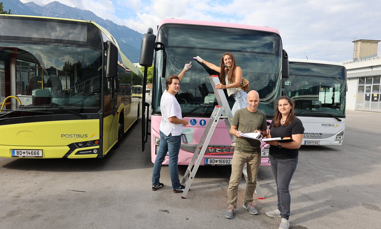 Vier Personen stehen vor einem Bus