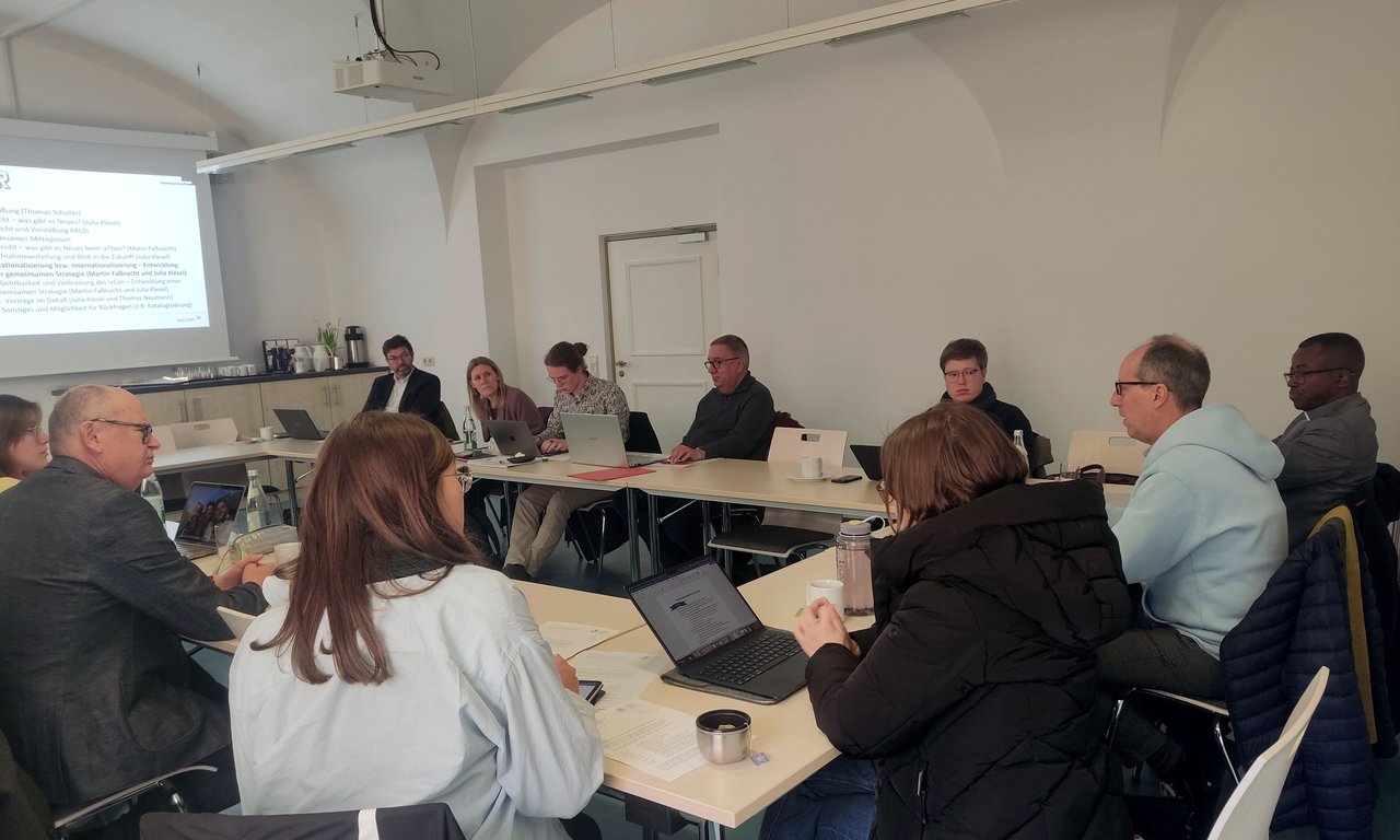11 Personen sitzen an Tischen in U-Form