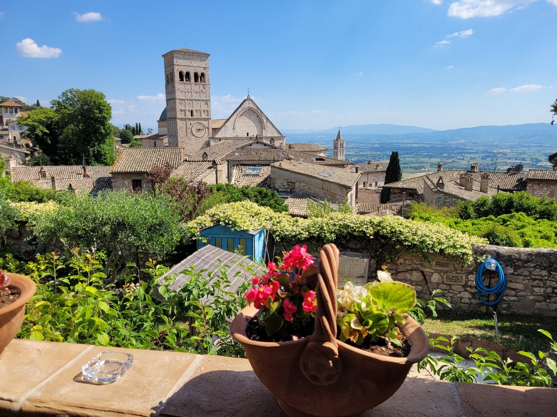 Zu sehen ist die Landschaft von Assisi, in der Mitte die Basilika.
