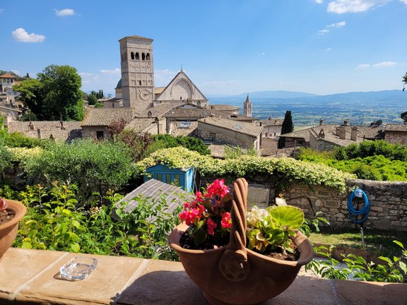 Zu sehen ist die Landschaft von Assisi, in der Mitte die Basilika.