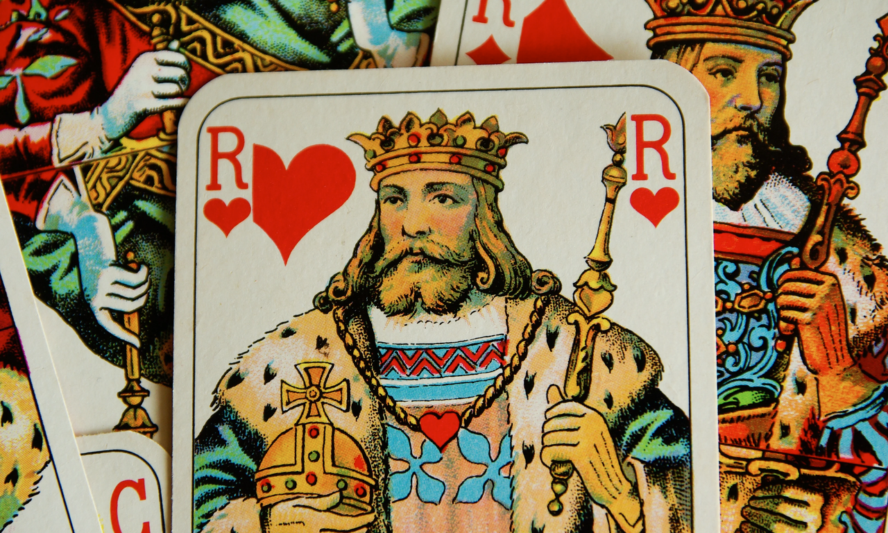 Das Bild zeigt eine Nahaufnahme mehrere übereinanderliegender Spielkarten. Der Herzkönig steht im Zentrum, er ist mit Krone, Zepter und Reichsapfel dargestellt.