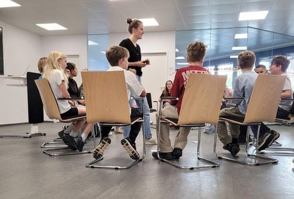 Kinder sitzen im Sesselkreis und hören zu