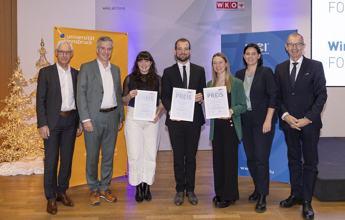 Gruppenfoto in der Räumlichkeiten der Wirtschaftskammer. Es zeigt die drei Preisträgerinnen , die die Urkunde in die Kamera halten mit Repräsentantinnen von WK und Hochschulen.