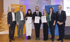 Gruppenfoto in der Räumlichkeiten der Wirtschaftskammer. Es zeigt die drei Preisträgerinnen , die die Urkunde in die Kamera halten mit Repräsentantinnen von WK und Hochschulen.