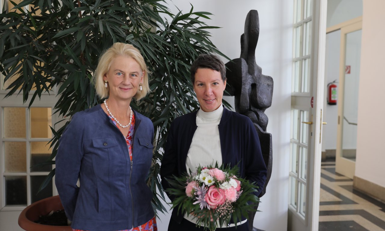Veronika Sexl, Rektorin der Universität Innsbruck, steht im blauen Blazer links neben Wissenschaftlerin Gundula Ludwig, die einen rosa Blumenstrauß in der Hand hält.