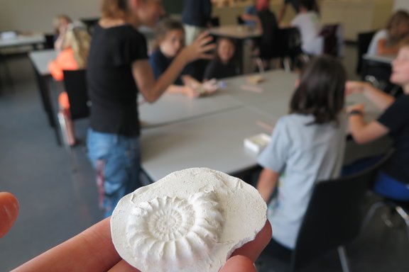 Ein Kind zeigt ein selbstgemachtes Fossil