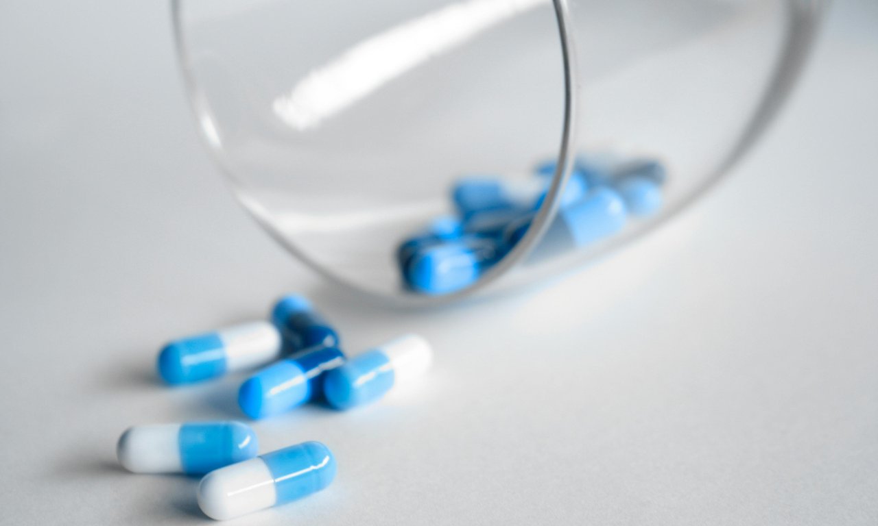 Tabletten fallen aus einem umgekippten Glas