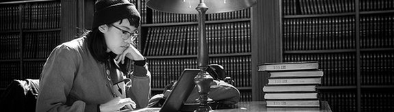 Studentin sitzt in einer Bibliothek am Laptop