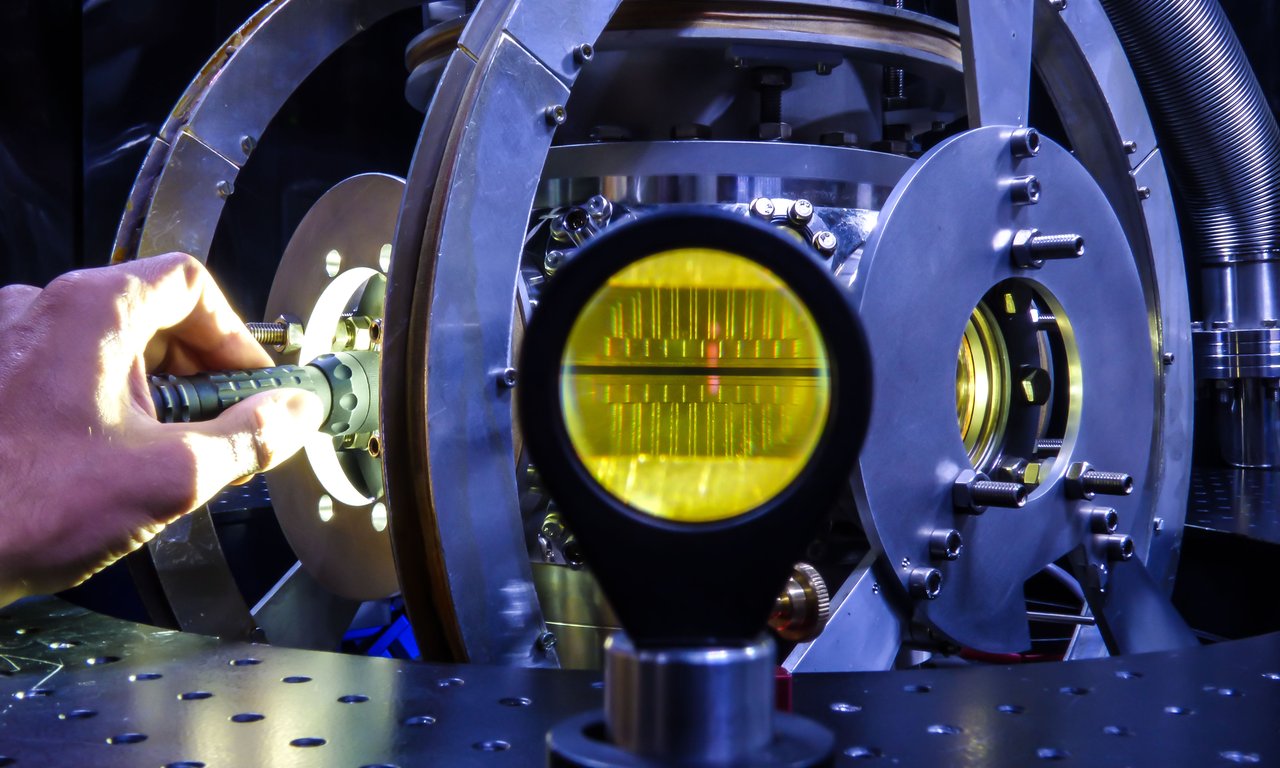 View into a vacuum chamber, a hand shines a flashlight into the chamber