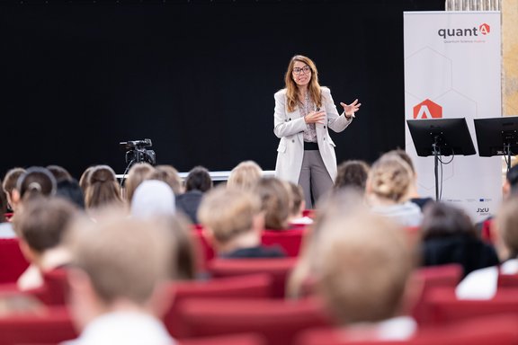 Ferlaino auf einer Bühne vortragend, im Vordergrund Jugendliche