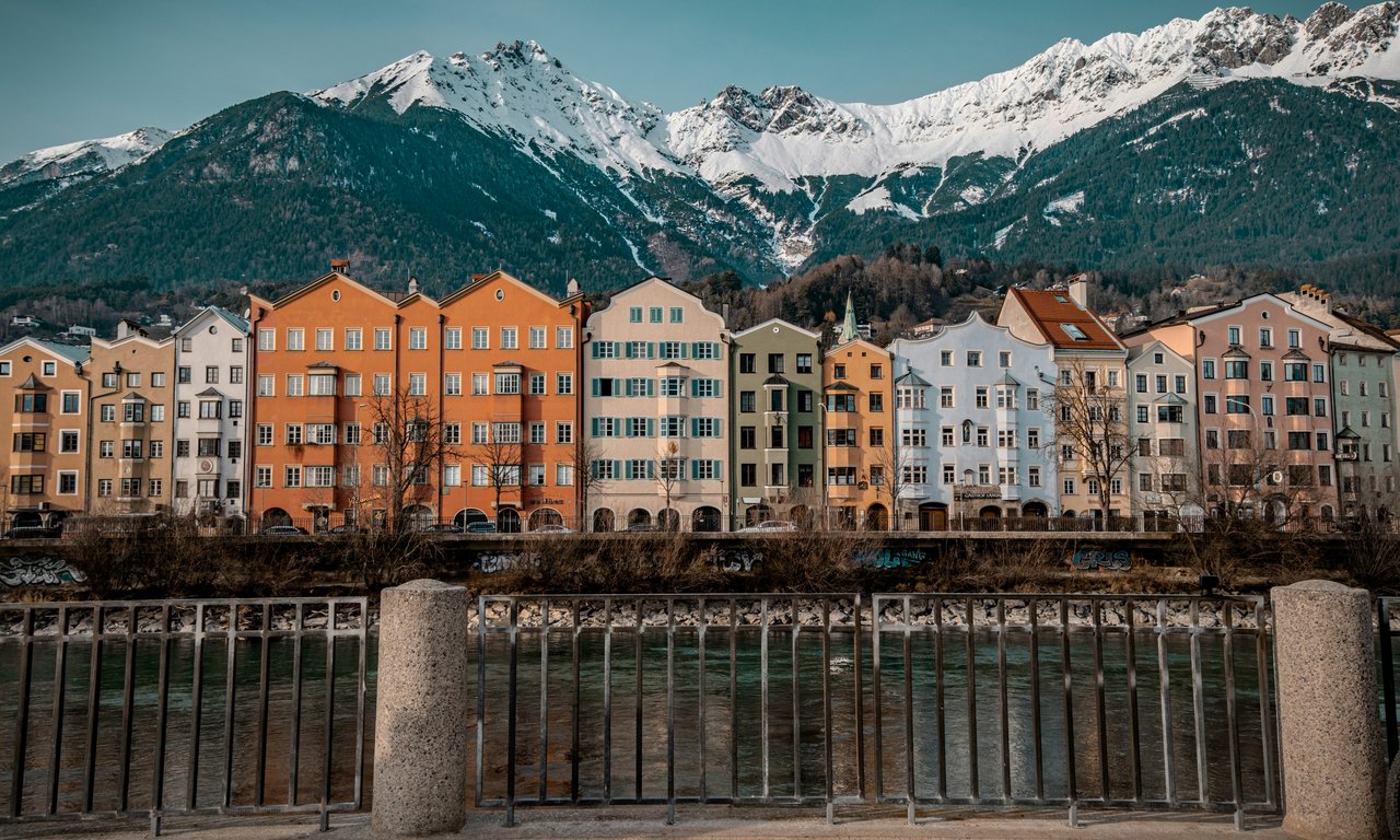 Blick auf Mariahilf quer über den Inn, bunte Häuserfronten im Vordergrund, die schneebedeckte Nordkette im Hintergrund