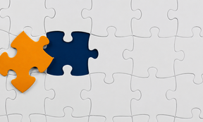 Weißes Puzzle mit einem orangen Puzzlestück, das noch fehlt