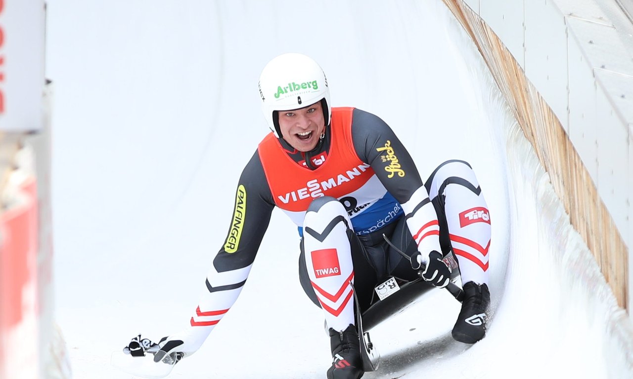 Rodler in einem Eiskanal mit einer Hand auf der Eisfläche
