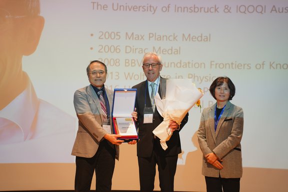 Drei Personen mit Urkunde