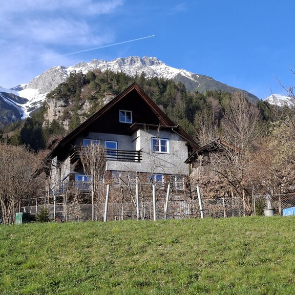 Altes Wohnhaus vor schneebedeckter Bergkulisse