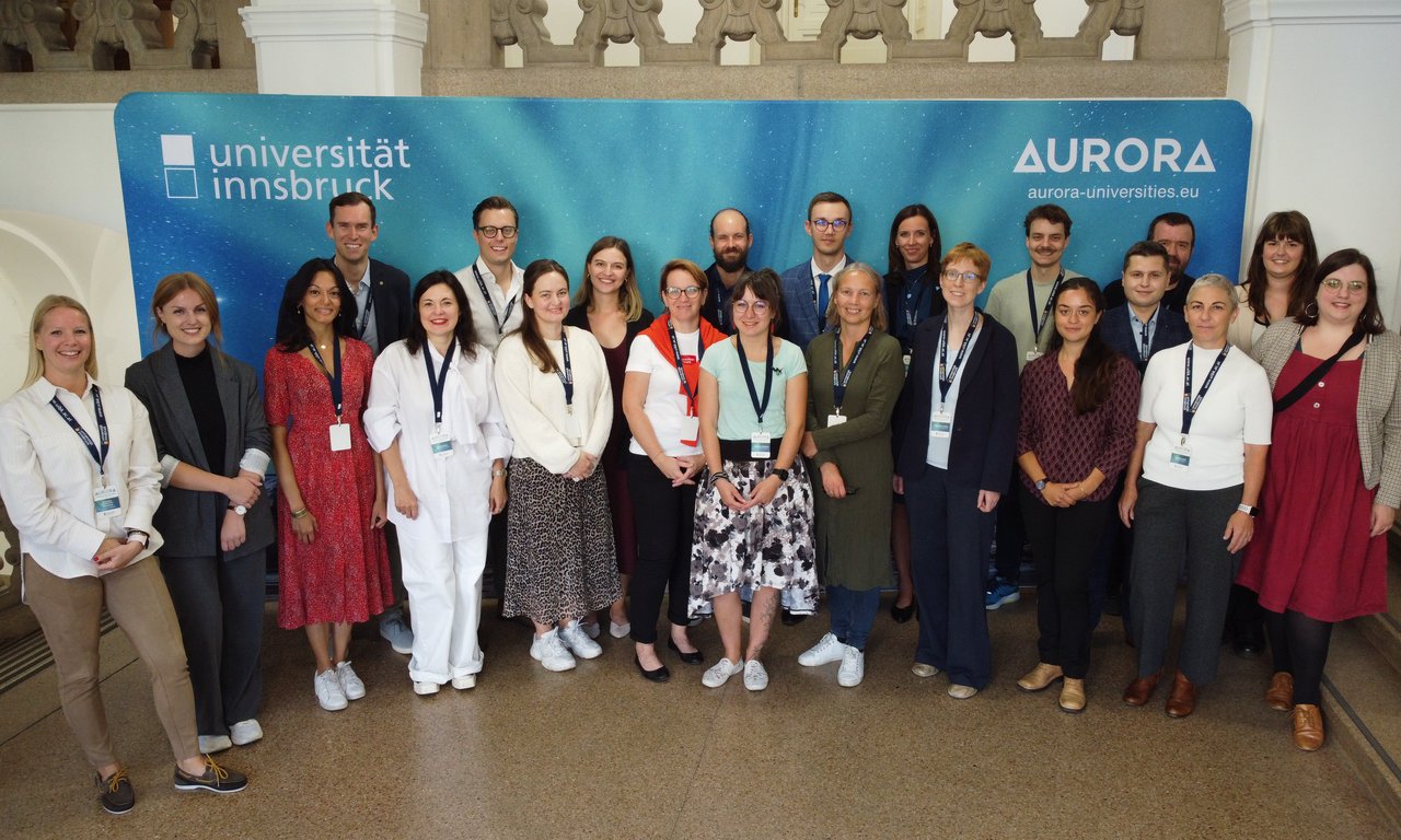 Gruppenbild von ca. 20 Personen vor einer Pressewand mit den Logos der Uni Innsbruck und Aurora