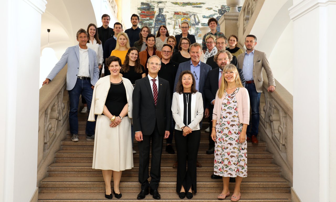 Die Mitglieder des Senats der Universität Innsbruck stehen für ein Gruppenfoto im Stiegenhaus des Universitätshauptgebäudes