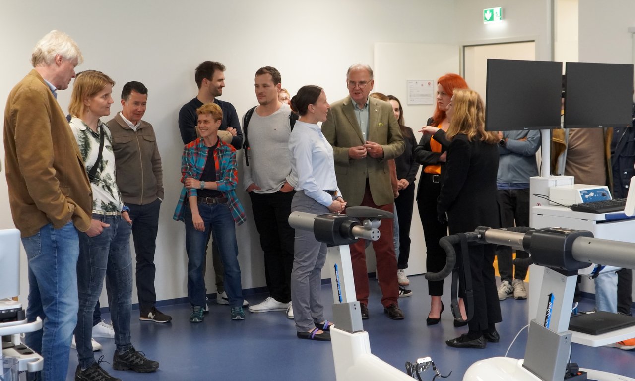 Zahlreiche Personen stehen in einem Raum mit Sportgeräten