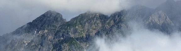 Berggipfel einer Bergkette eingehüllt in neblige Wolken