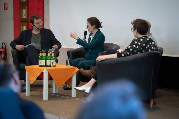 drei Personen bei einer Podiumsdiskussion
