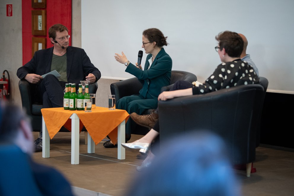 drei Personen bei einer Podiumsdiskussion