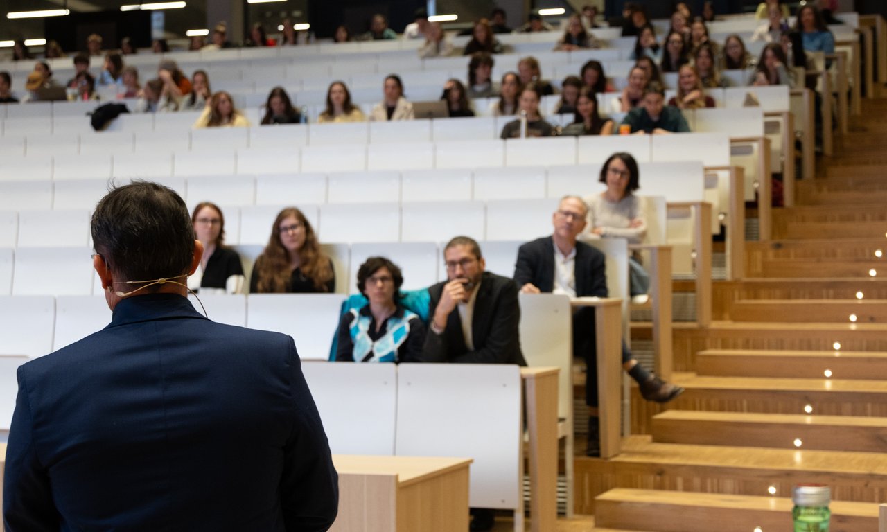 Bild von vorne auf einen halb gefüllten Hörsaal