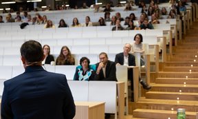 Bild von vorne auf einen halb gefüllten Hörsaal