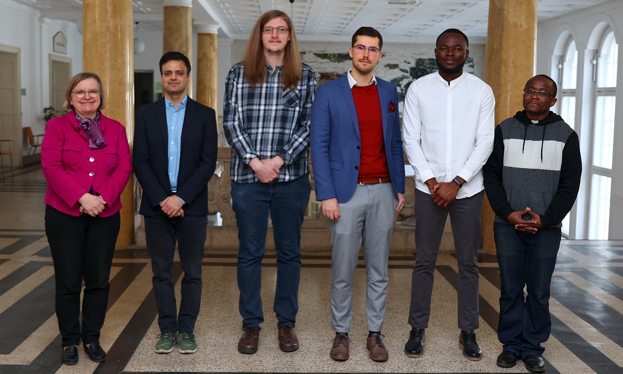 Sechs Personen stehen für ein Gruppenfoto im Gangbereich des Universitäts-Hauptgebäudes.