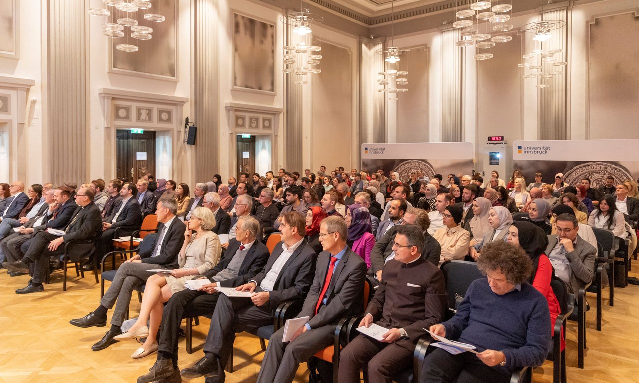 Publikum in der vollbesetzten Aula der Universität.