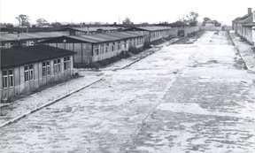 Schwarz-weiß-Foto, das einen größeren Platz und seitlich mehrere Baracken in der Gedenkstätte Mauthausen zeigt.