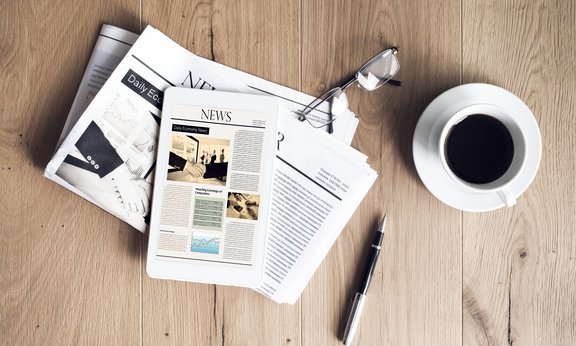 Tablet und Zeitungen neben Kaffeetasse und Brille - Nachrichten lesen