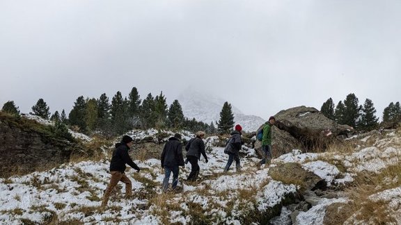 Five people hiking in the snow, misty mountains in the background, a waterfall in the foreground