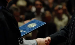 Zu sehen ist die Übergabe eines Abschlusszeugnisses.