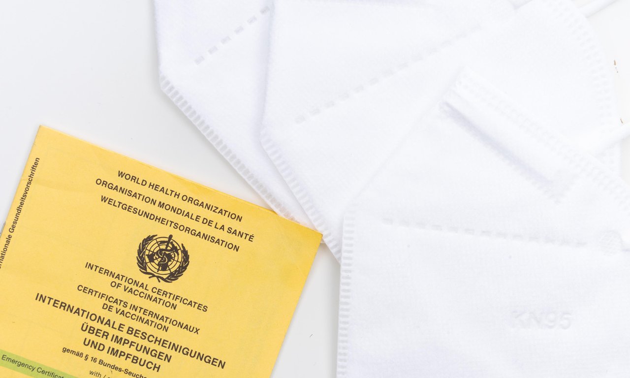 Ein Imfpass liegt auf zwei FFP2 Masken