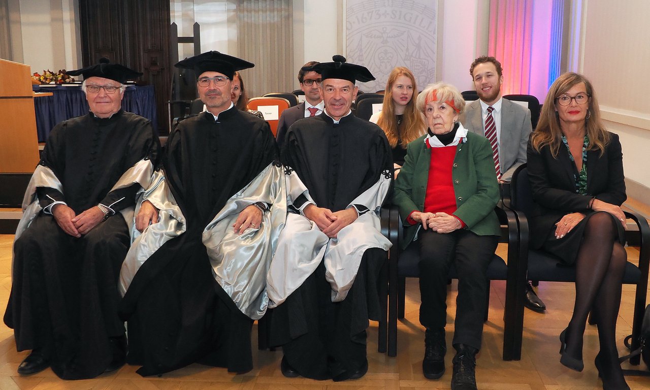 Mehrere Personen in Talaren sitzen in einer Reihe