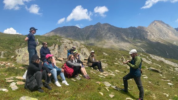 A group of people on a mountain slope talking one person.