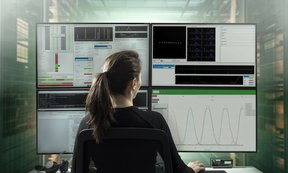 Eine Person sitzt vor mehreren Bildschirmen