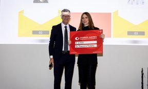 Links steht ein Mann im Anzug mit Mikrofon, daneben steht Francesca Finotello mit einem großen Schild mit dem Logo von Casinos Austria, auf dem groß die Summe des Preisgelds steht (2.000 Euro).